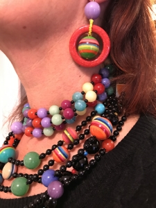 Dettaglio delle collane indossate da Sandra, un mare di colori che regalano vivacità e brio al tuo look. Particolare degli orecchini, realizzati con elementi in plexiglas multicolor.