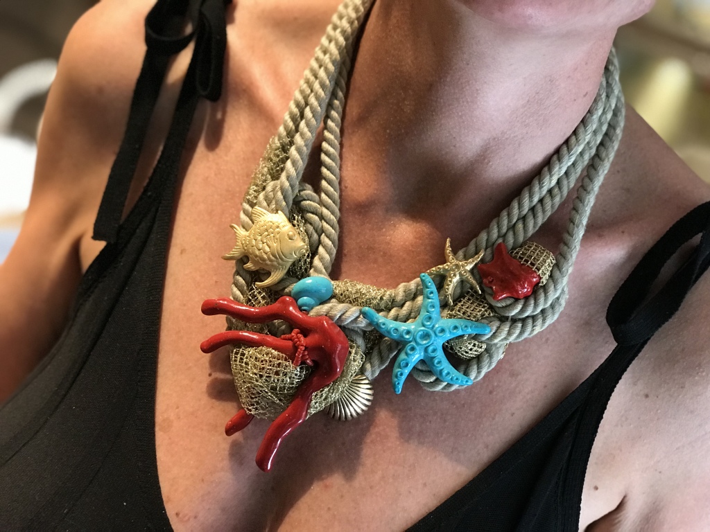 Dettaglio della collana indossata da Sabrina. Realizzata con una base in cordoni di cotone neutri ed elementi in plexiglas a tema marino, Ogni pezzo è cucito sapientemente a mano con fine tecnica sartoriale, bellissima la rete in lurex dorata che si insinua tra i cordoni e gli elementi, creando un effetto luminoso e scenografico. E' un pezzo unico di Cillabijoux