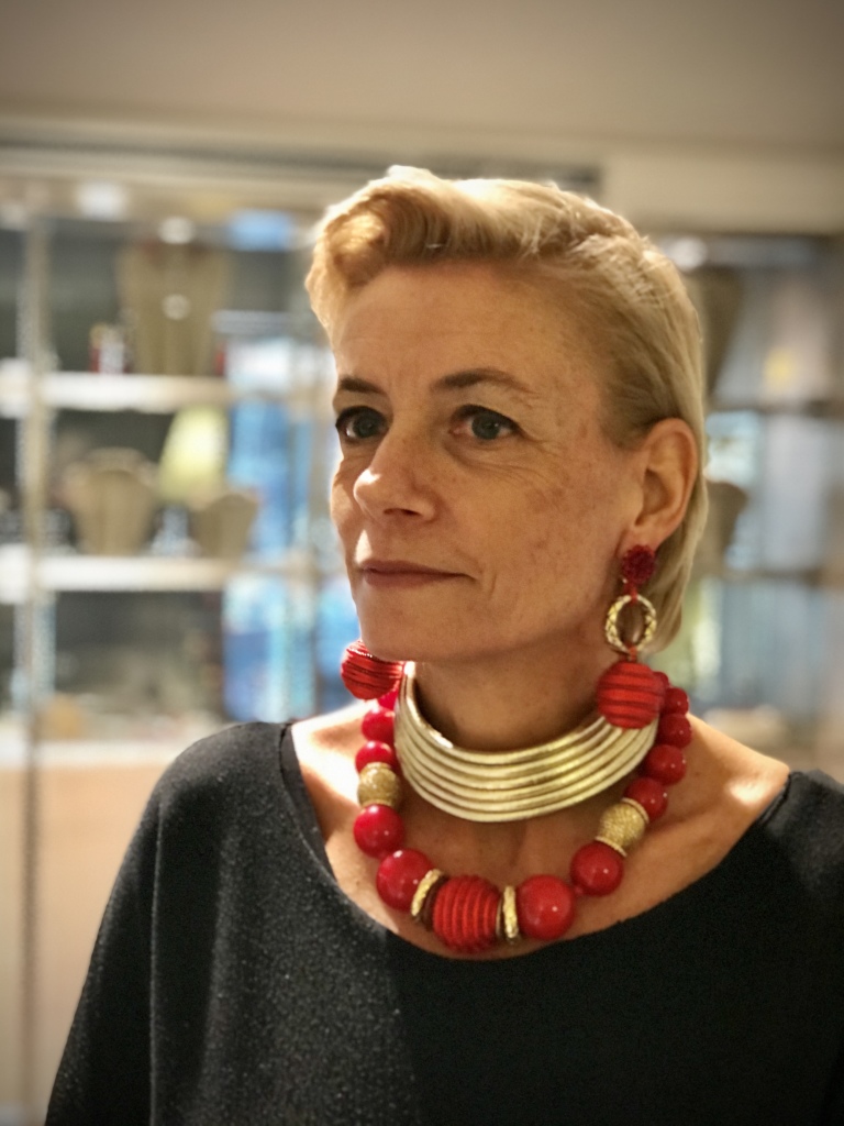 Sabrina indossa un collier de chain in morbidi fili tubolari di vera pelle dorata: luminosità esagerata in un bijoux estremamente elegante e raffinato nella sua essenzialità. Girocollo di boulle in plexiglas rosso vivo intervallate da rondelle dorate, sfere ricoperte a mano con filato in passamaneria dorata e meravigliosa sfera centrale, interamente ricoperta a mano con passamaneria in seta e cristalli rossi. Orecchini pendenti con bottoni lavorati a mano in Cristallo di Boemia rosso, cerchi in plexiglas metallizzato dorato con lavorazione a effetto serpe e grande sfera interamente ricoperta a mano con passamaneria in seta e cristalli rossi.