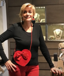 Sabrina indossa maxi orecchini in plexiglas con doppio cuore, uno nero e uno rosso e una deliziosa pochette a forma di cuore, rosso fuoco.  La pochette è un pezzo unico, interamente cucita a mano, con grande fiocco in velluto e cordino in seta.