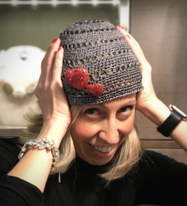 Raffy indossa un cappellino a calotta in lurex grigio argento con due spille a cuore ricoperte di strass Swarovski rosso vivo.