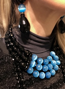 Dettaglio dei gioielli: Collier de chain a tre fili di Cristalli Jais nero e azzurri e collane lunghe, tutte realizzate interamente a mano con elementi in Onice, Cristalli in Jais nero e azzurri. Luminosità eccezionale ed un tocco di colore che renderà unico anche un look semplice total black. Preziosi ed eleganti questi gioielli regaleranno un'allure sofisticata e glamour al tuo look. Maxi orecchini in cristallo con grande goccia Jais nero.