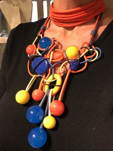 Particolare dei bijoux indossati da Sabrina. Collier de chain a fascia, in filato di cotone cerato, in una calda nuance arancione; Collana - scultura modellata a mano con fine tecnica artigianale, realizzata con filato in cotone cerato ed elementi e boulle in plexiglas. Colore ed originalità per questa creazione davvero particolare, che certamente non passa inosservata, è un pezzo unico di Cillabijoux.