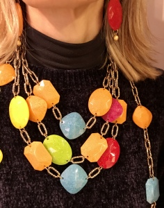 Dettaglio dei bijoux indossati da Raffy: Girocollo, collana lunga portata girata due volte e collana lunga semplice e bracciale... un tripudio di colori per vivacizzare i tuoi look! Coloratissimi elementi geometrici in plexiglas intervallati da una particolare catena dorata ad effetto martellato, ultra luminosa.