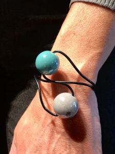 Dettaglio del bracciale indossato da Sabrina, dalla forma sinuosa ed essenziale, si modella al polso senza chiusure. Da notare la luminosità delle boulle in ceramica, in raffinate nuance grigio e turchese.